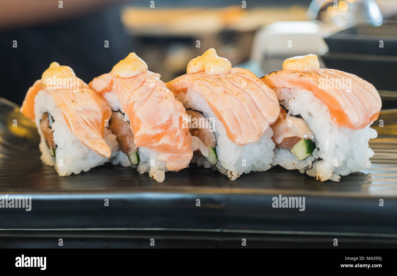 Pavé de saumon sushi roll, nourriture japonaise sur style plat de céramique noire Banque D'Images