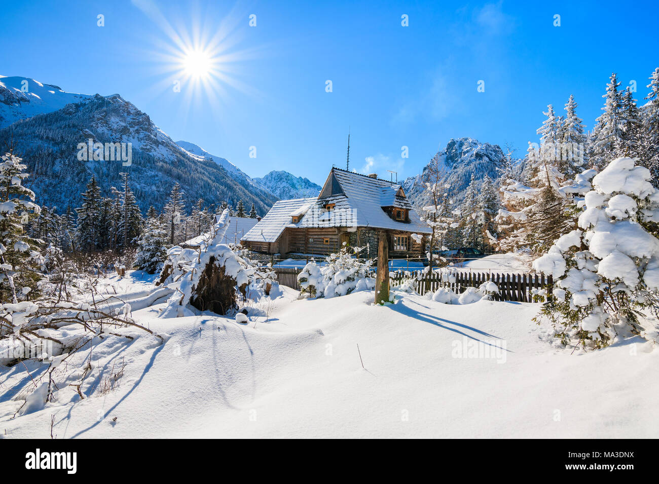 Petite maison en bois en hiver paysage près du lac Morskie Oko avec soleil sur ciel bleu, Tatras, Pologne Banque D'Images