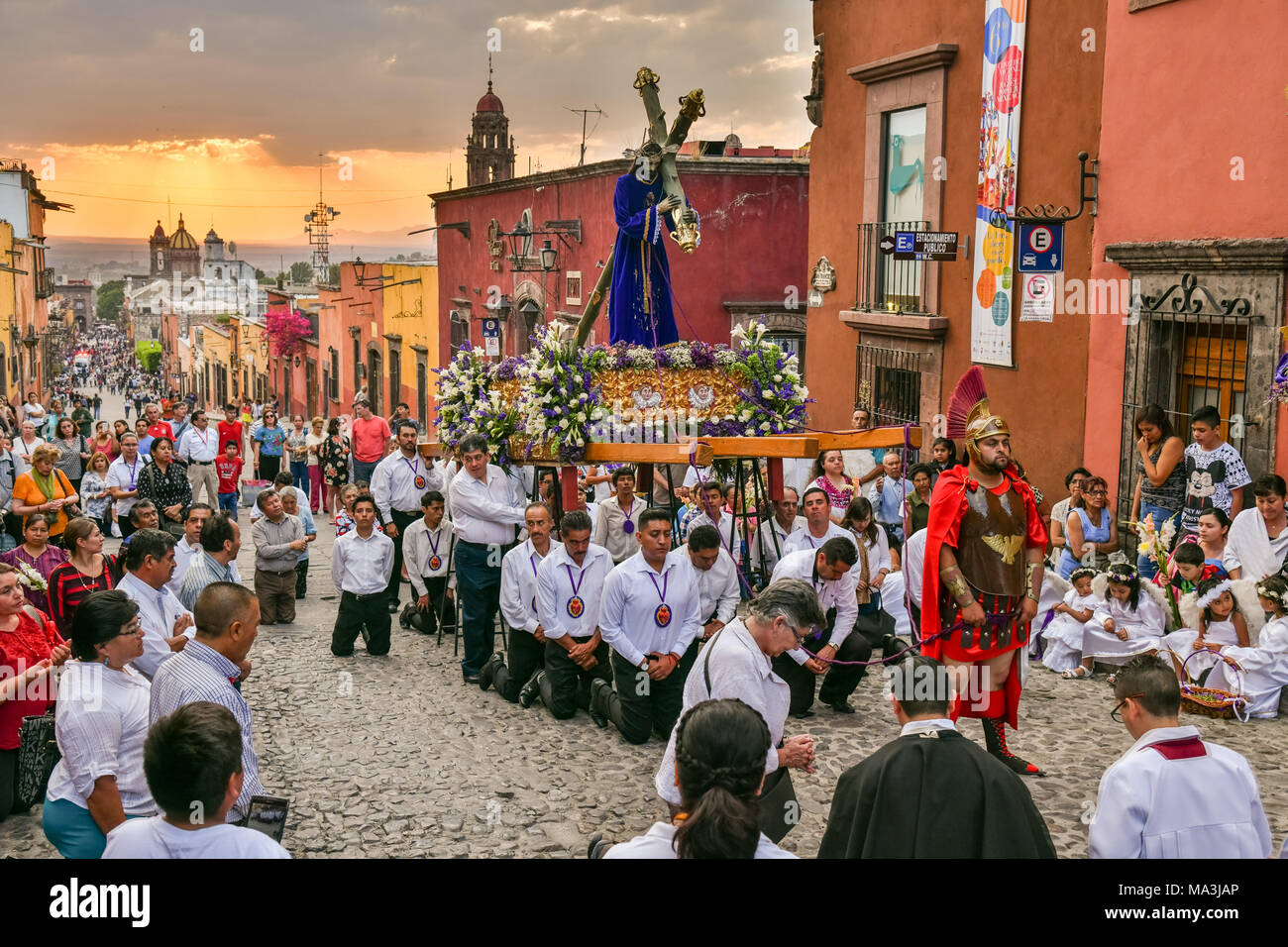 Les fervents catholiques à genoux dans la prière pendant le Las Cruzes del Señor Golpe procession à travers les rues au coucher du soleil dans le cadre de la Semaine Sainte le 28 mars 2018 à San Miguel de Allende, Mexique. L'événement est la récréation de la passion de Jésus Christ sur le chemin de calvaire pour la crucifixion. Banque D'Images