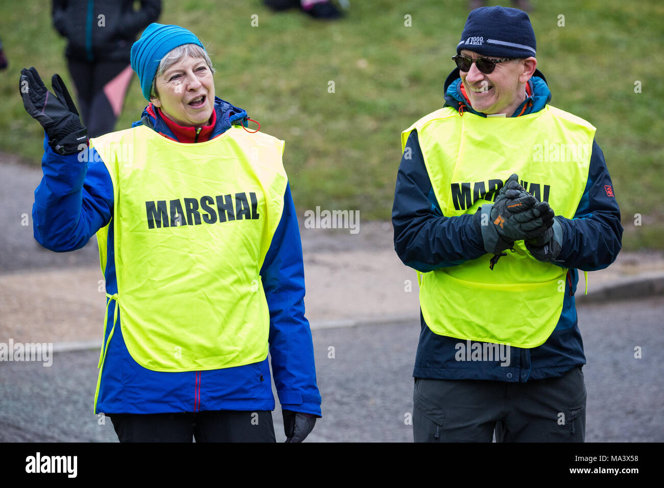 Maidenhead, Royaume-Uni. 30 mars, 2018. Premier ministre Theresa mai vagues à un coureur alors qu'elle et son mari Philip peuvent agir comme agents de sécurité à l'assemblée annuelle de Pâques course de bienfaisance 10 Maidenhead le Vendredi saint. Credit : Mark Kerrison/Alamy Live News Banque D'Images