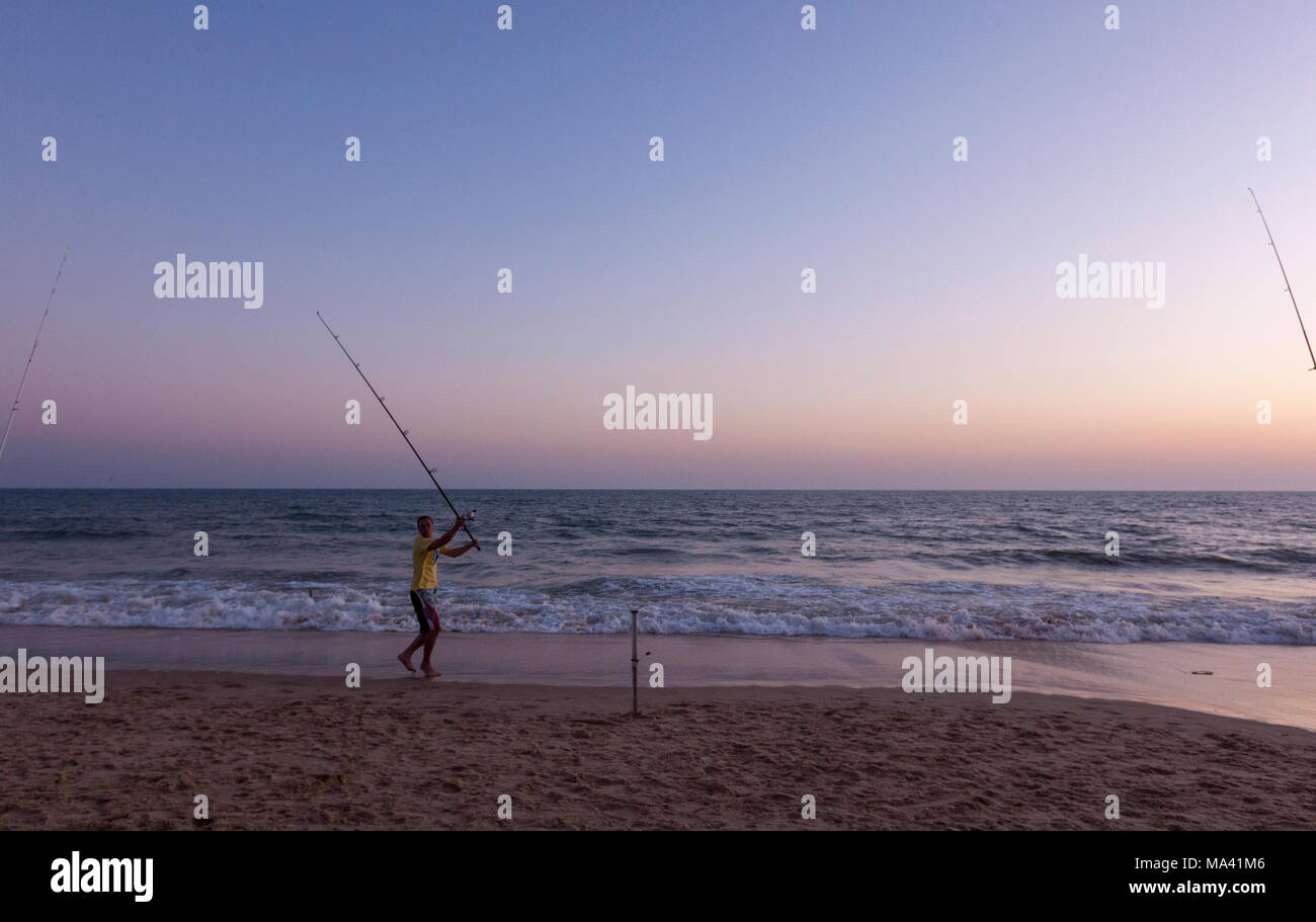 L'homme Pêche avec tige du rabatteur de Matalascañas plage au crépuscule, Almonte, Province de Huelva, Andalousie, espagne. Banque D'Images