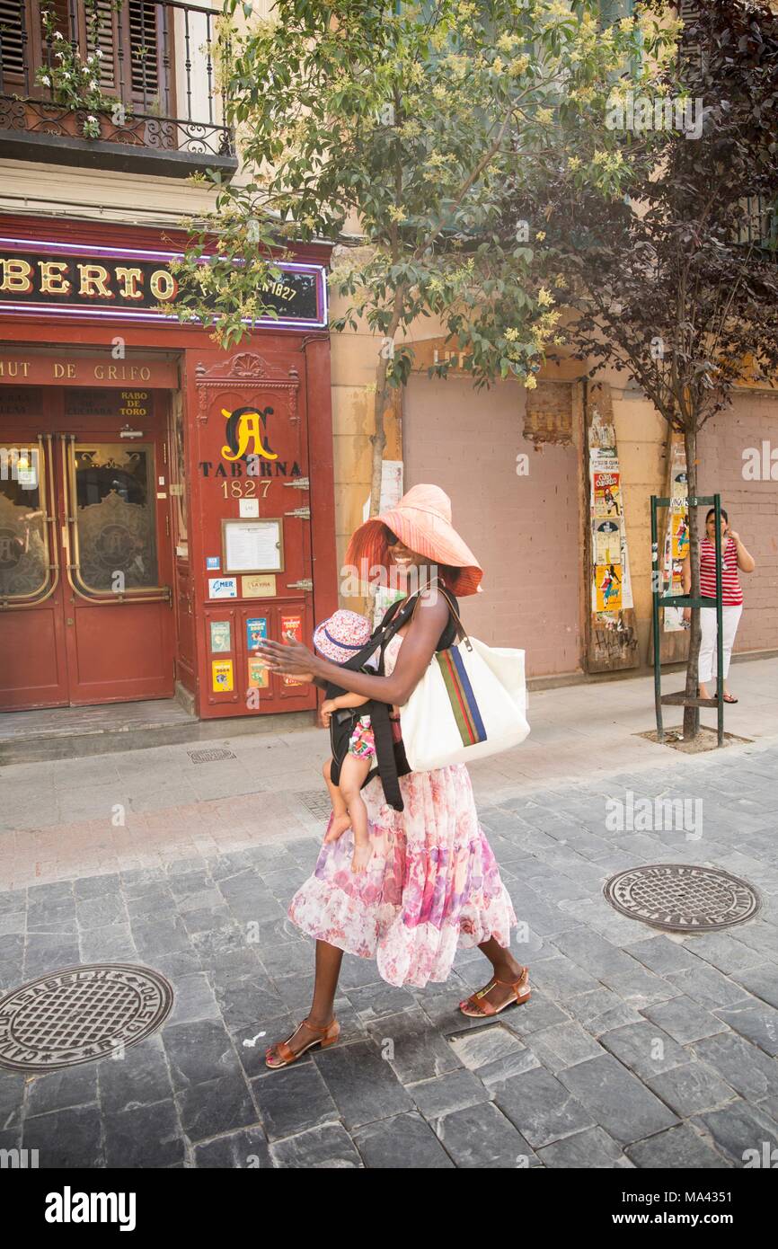 Une mère portant un enfant, marcher le long de la Calle de las Huertas à Madrid, Espagne Banque D'Images