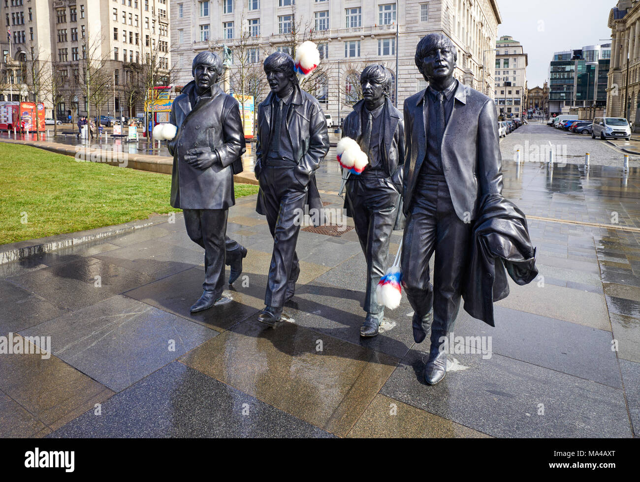 Beatles statues at Pier Head à Liverpool avec bâtonnets de chatouilles ajoutée à la mémoire de Ken Dodd de funérailles le 28 mars 2018 Banque D'Images