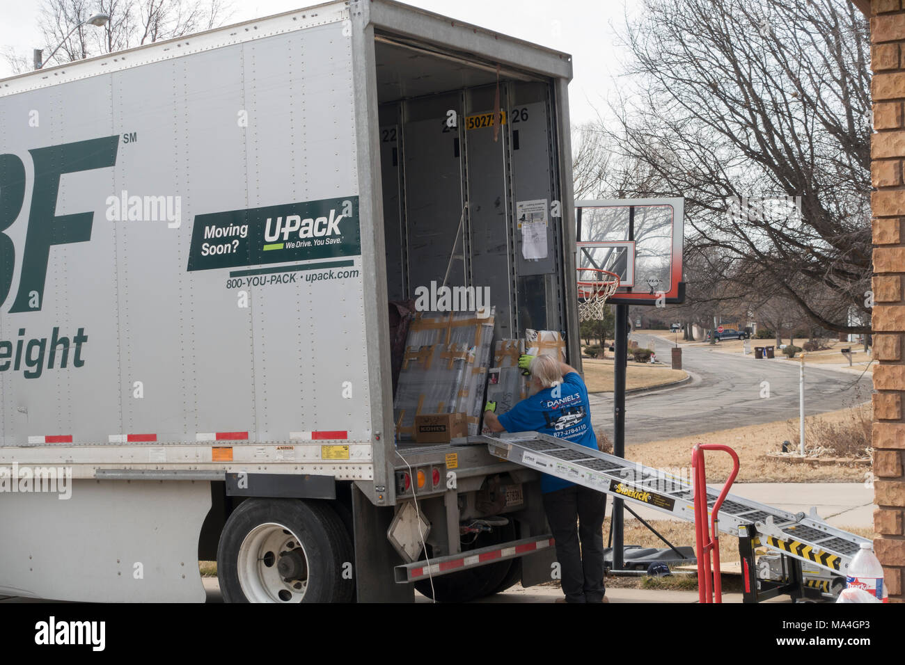 Un homme de race blanche aux cheveux blancs de déchargements des biens ménagers d'un ABF UPack ou camion de déménagement dans la région de Wichita, Kansas, États-Unis. Banque D'Images