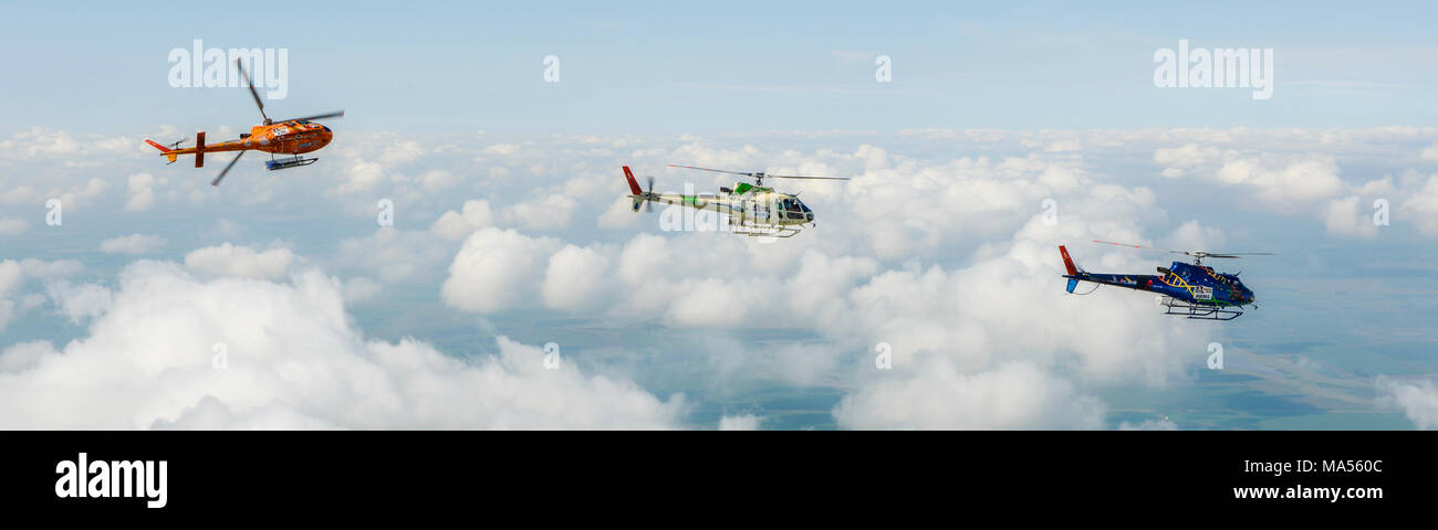 L'air de l'air photo panorama de trois hélicoptères Airbus colorés comme350 B3 Ecureuil AStar (Squirrel), volant au-dessus des nuages et Argentine pampa Banque D'Images