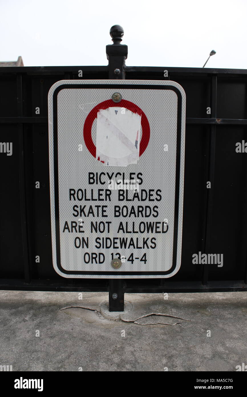 Panneau routier interdisant les vélos, rollers, planches à roulettes et de riding sur le trottoir avec le signe n'entrez pas effacés dans un cercle rouge. Banque D'Images