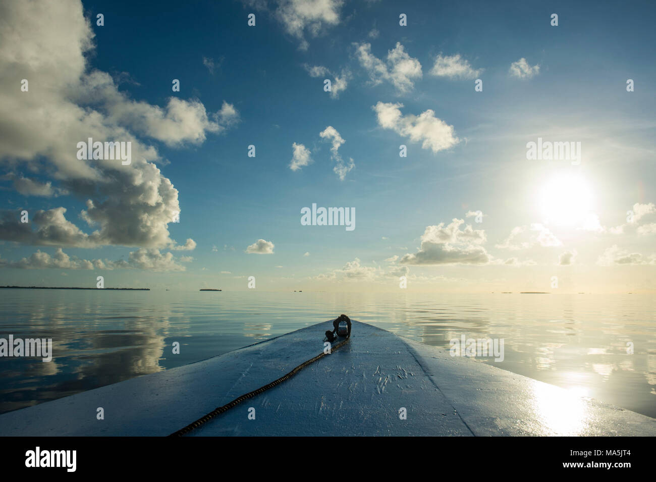 Détail du bateau, le soleil, les nuages se reflétant dans les eaux calmes de Tikehau, Tuamotu, Polynésie Française Banque D'Images