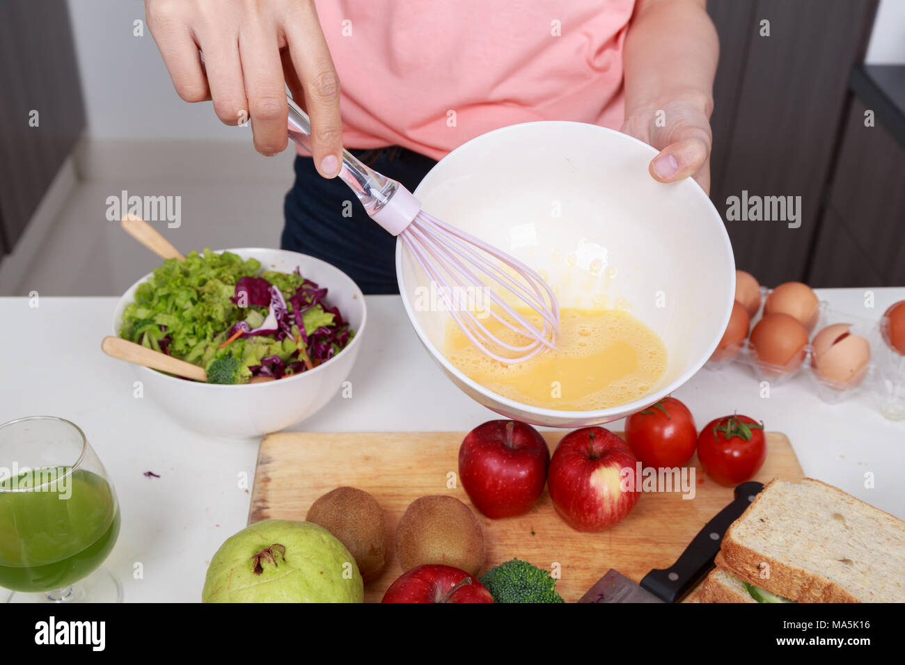 Close up of hand et la cuisson en fouettant les oeufs dans un bol dans la cuisine prix Banque D'Images