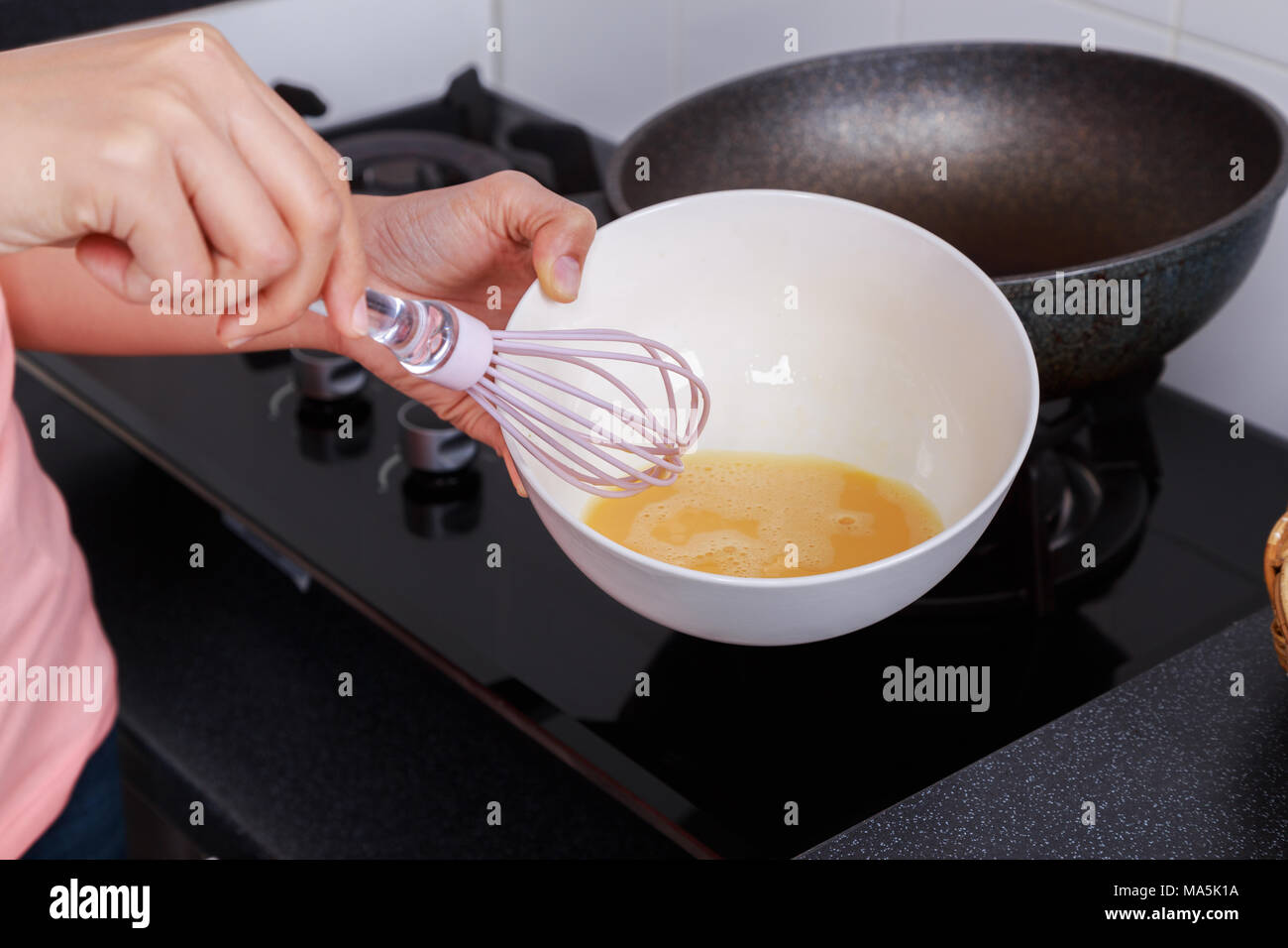 Close up of hand et la cuisson en fouettant les oeufs dans un bol dans la cuisine prix Banque D'Images