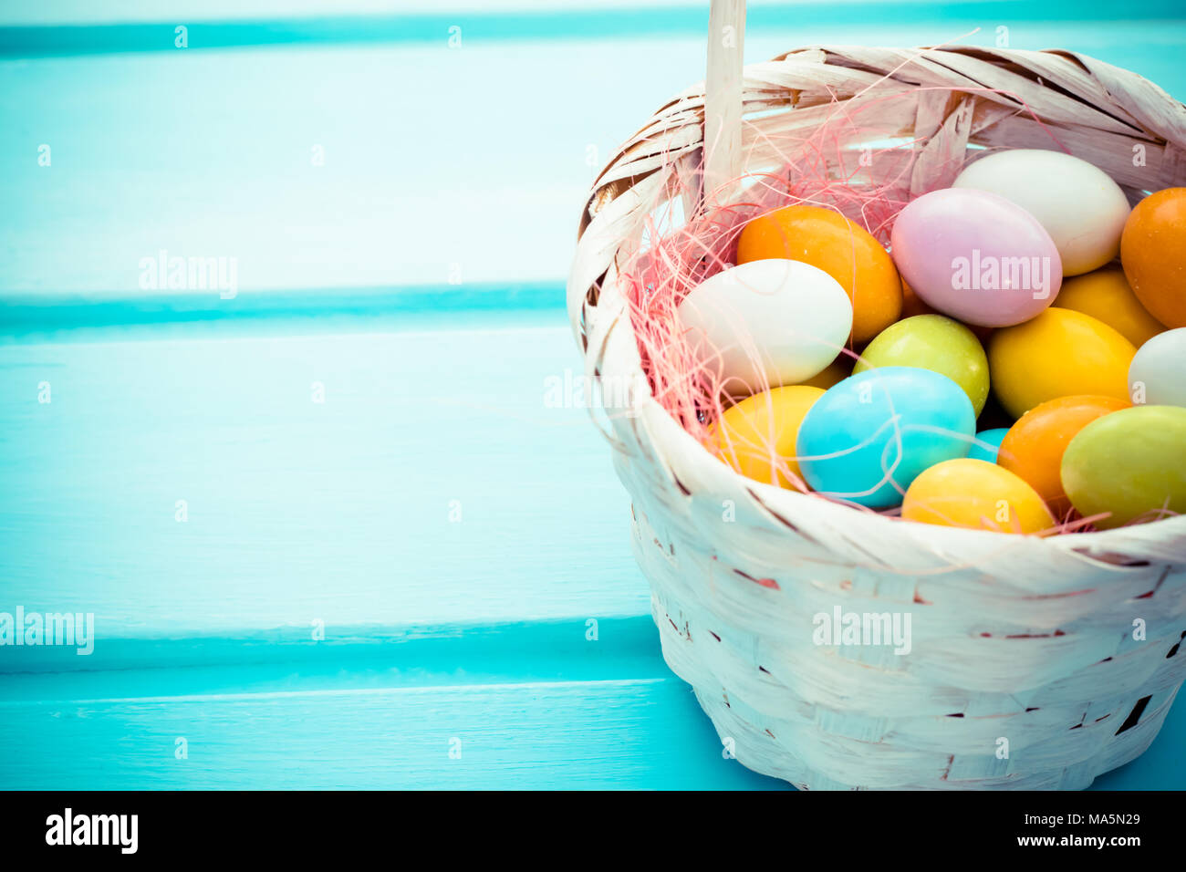 Oeufs de Pâques doux colorés en blanc turquoise panier de paille sur fond de bois. Copyspace Banque D'Images