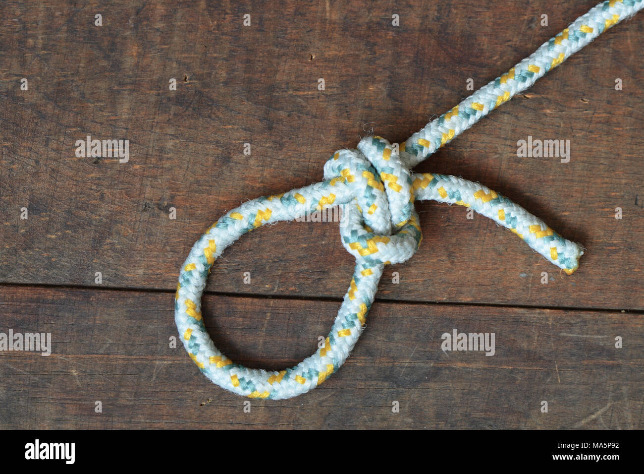 Corde avec noeud et boucle allongée sur fond de bois Banque D'Images