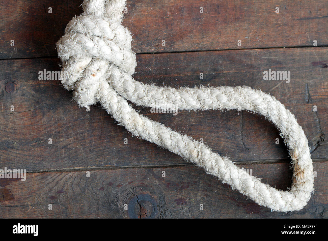 Vieille corde épaisse avec noeud et boucle allongée sur fond de bois Banque D'Images