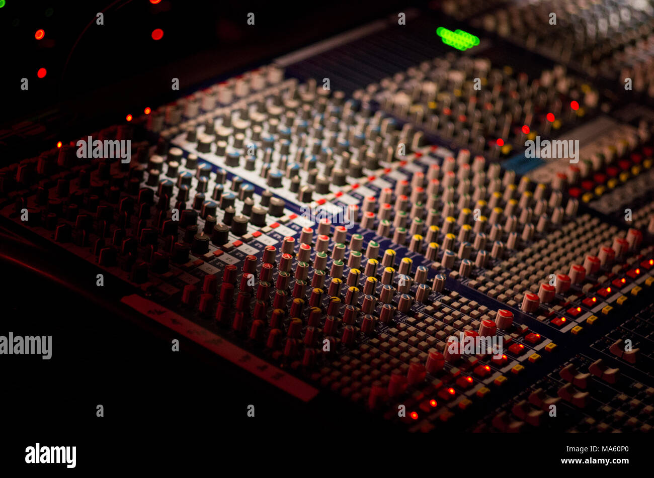 Table de mixage avec le sait et voyant vert s'allume dans un lieu sombre avec une profondeur de champ étroit Banque D'Images