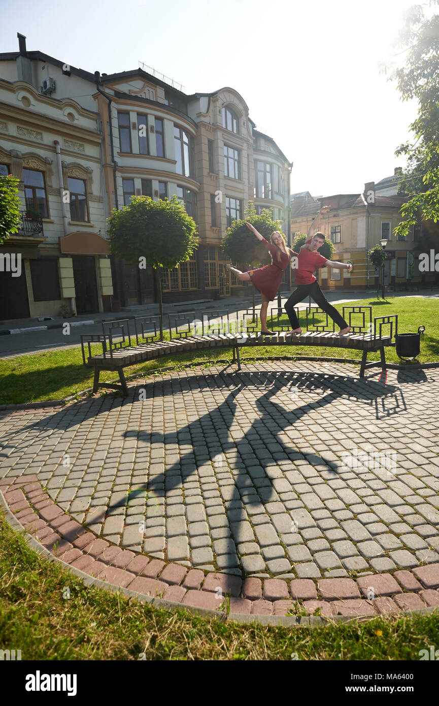 Ivano-Frankivsk, Ukraine - 1 juin 2015 : beau jeune couple danse sur banc de la ville à proximité de plantes vertes et de façade du bâtiment d'origine. Garçon et fille à heureux, satisfaits et émotionnel. Banque D'Images