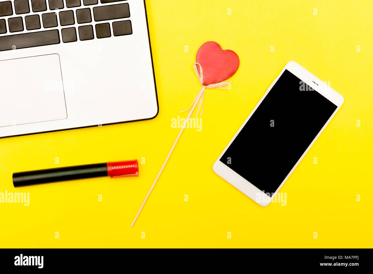 Symbole coeur d'un ordinateur portable smartphone. Un cœur décoratif sur un fond jaune avec smart gadgets. Banque D'Images