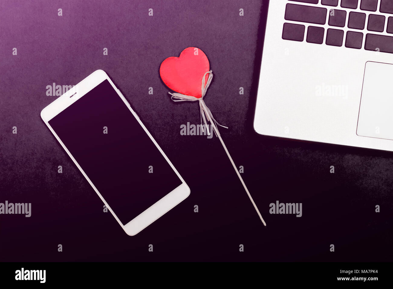 Symbole coeur d'un ordinateur portable smartphone. Un cœur décoratif sur un fond jaune avec smart gadgets. Banque D'Images