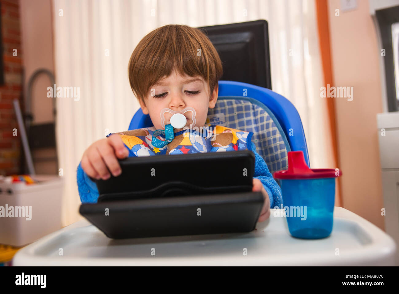 Jeune garçon regardant une tablette électronique tout en mangeant.Crédit : Mario Beauregard/Alamy Live News Banque D'Images