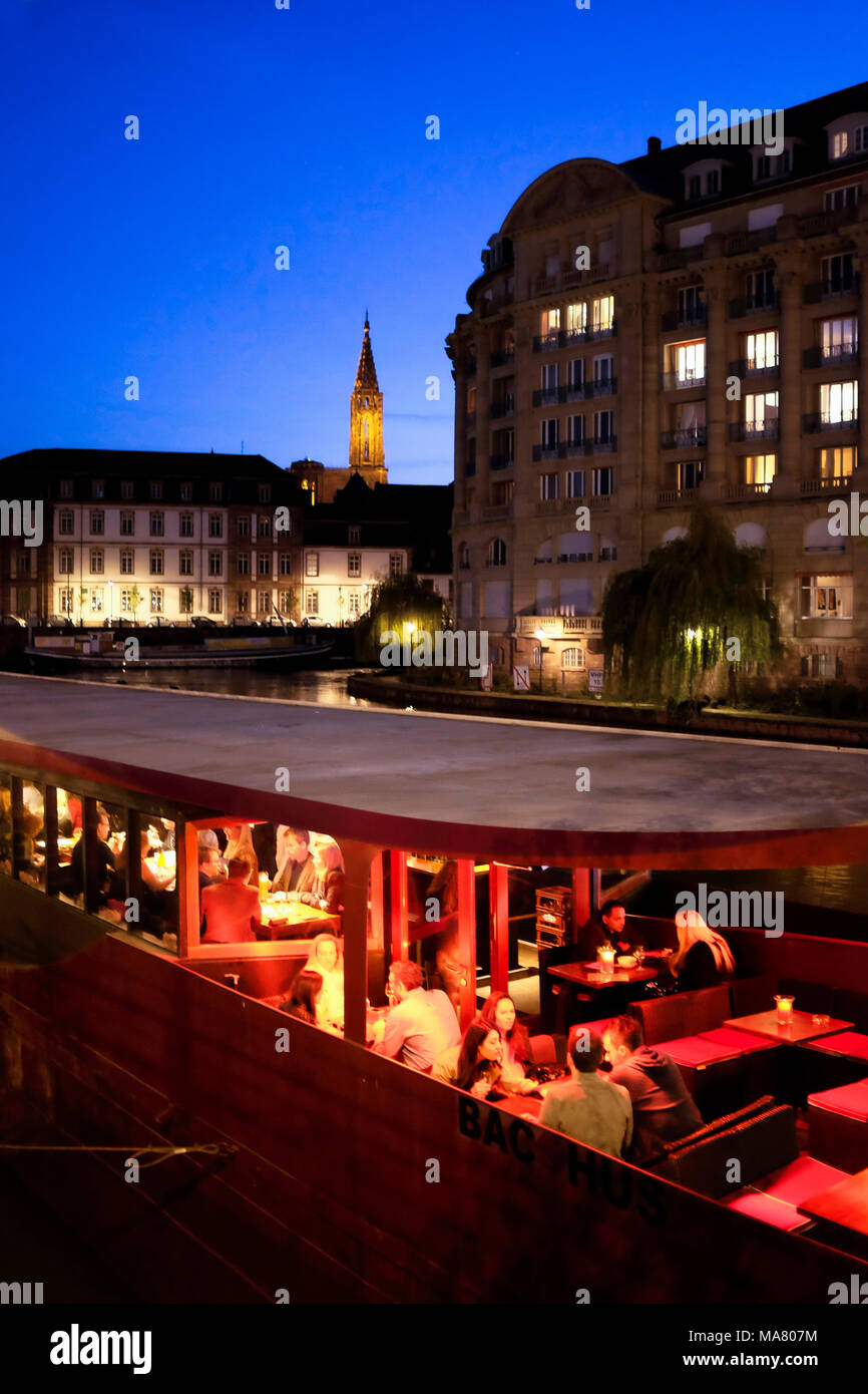 Terrasse de café sur la barge, bar sur le bateau, personnes, condo éclairé; flèche cathédrale, Nuit, Strasbourg, Alsace, France, Europe, Banque D'Images