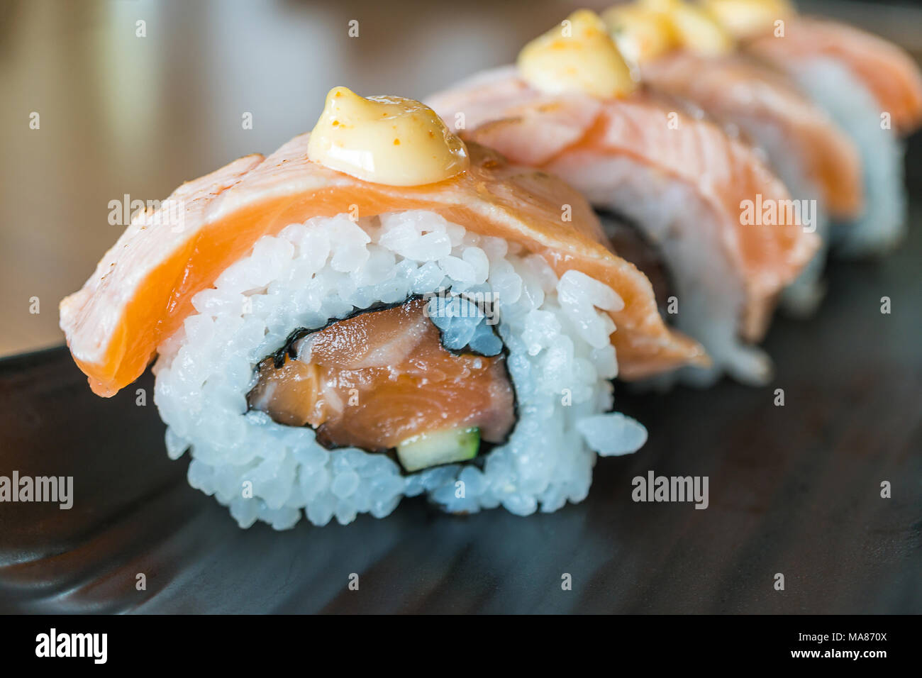 Pavé de saumon sushi roll, nourriture japonaise sur style plat de céramique noire Banque D'Images