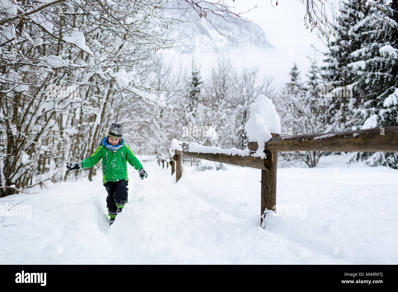 Balades dans la neige enfant souriant et arbres par une clôture en bois Banque D'Images