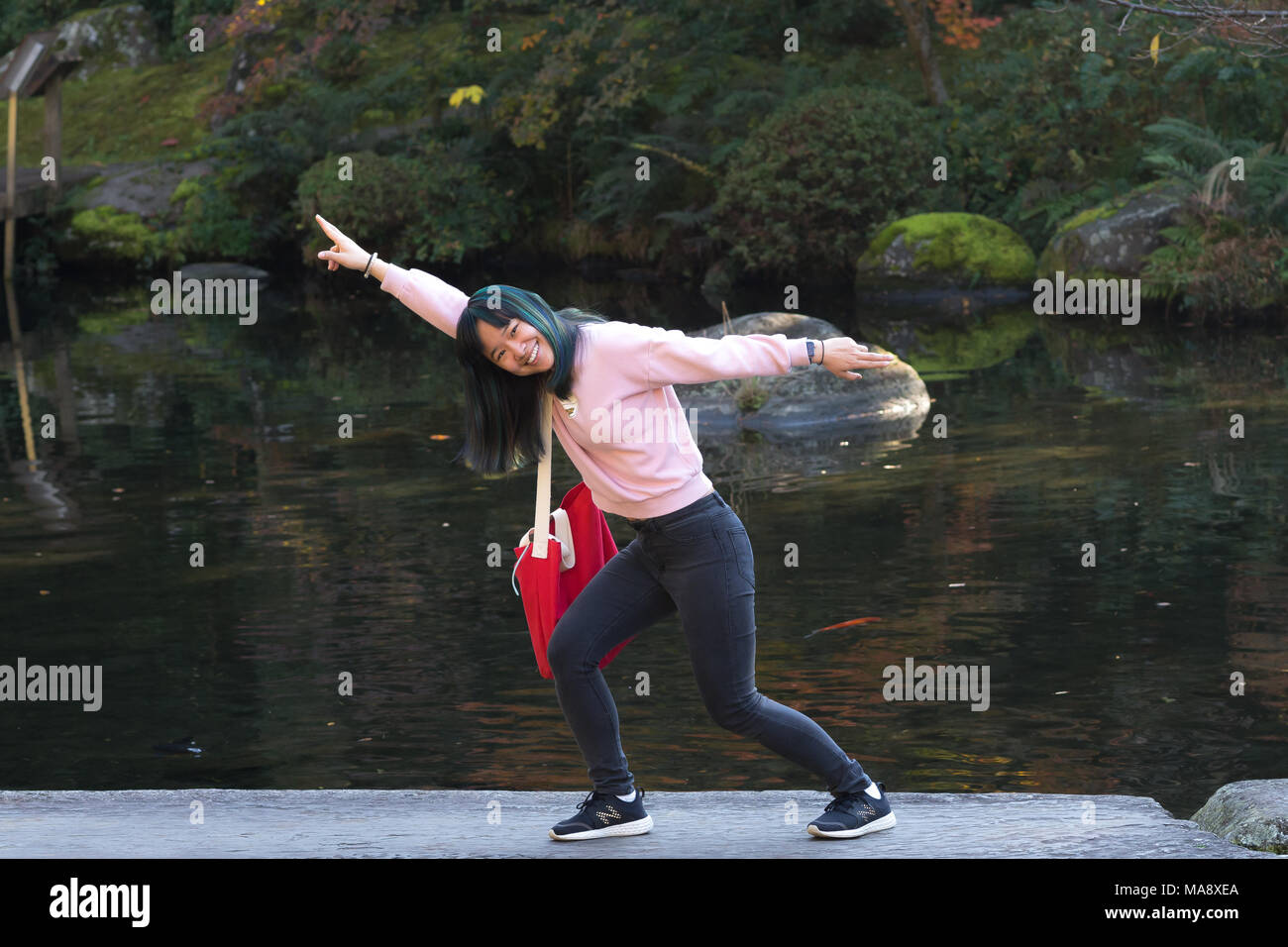 Jeune fille asiatique posant dans un jardin japonais près d'un étang de poissons Banque D'Images