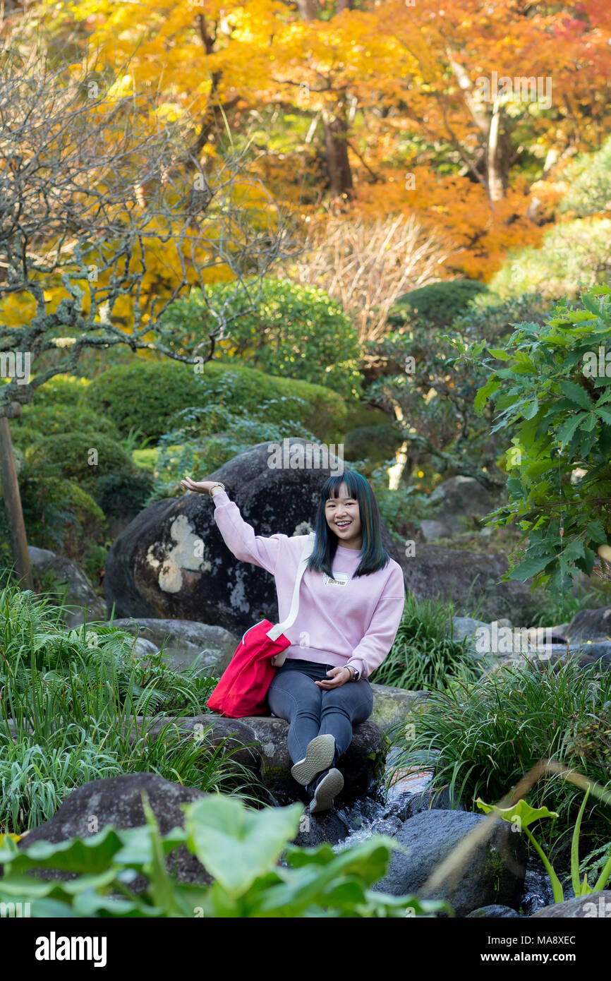 Jeune fille asiatique debout dans un jardin japonais dans le feuillage de l'automne Banque D'Images
