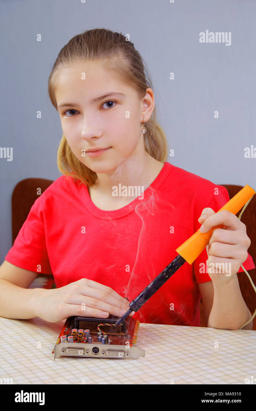 L'adolescent est d'apprendre à souder. Réparation d'une carte graphique de l'ordinateur Banque D'Images