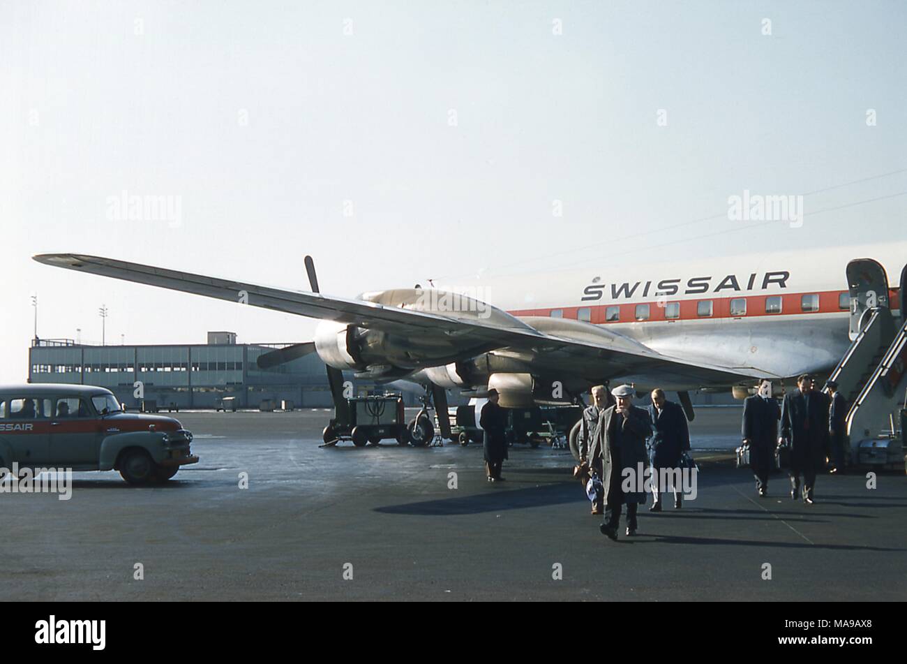 Scène de passagers débarquant d'un DC de Swissair HB 7C 'PRESS' Mers même avion sur le tarmac à l'extérieur du terminal des arrivées internationales, à l'Aéroport International de New York Idlewild, Jamaïque, Queens, New York, juin 1959. Au bord gauche juste au-delà de l'aile de l'avion et moteur à hélice est une voiture de l'aéroport de Swissair. () Banque D'Images