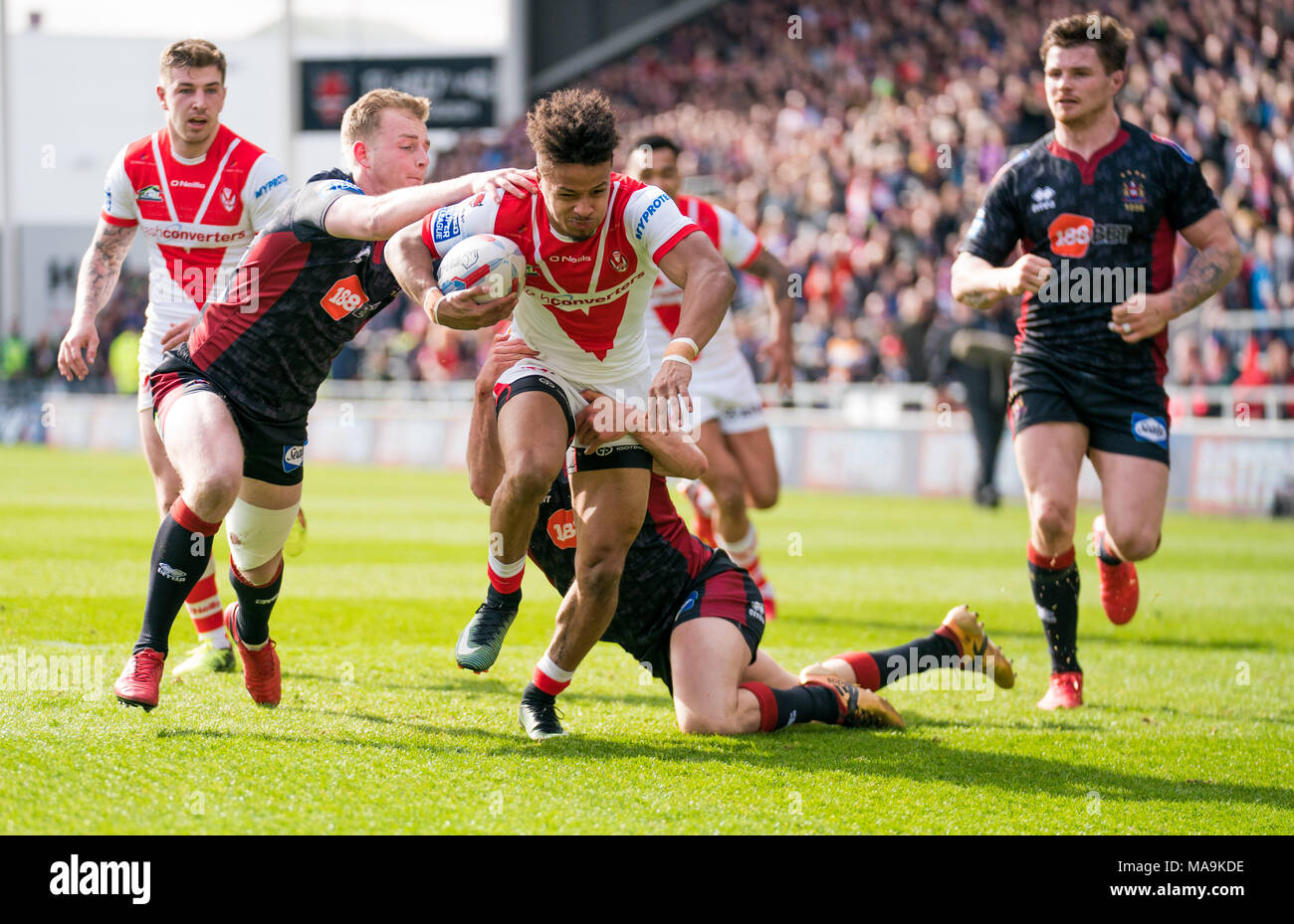 Saint Helens's Regan Grace est abordé par Wigan Warriors's Josh Woods 30 MARS 2018 , totalement méchant Stadium , Merseyside, Angleterre ; Betfred Super League rugby, ronde 8, St Helens v Wigan Warriors. Banque D'Images