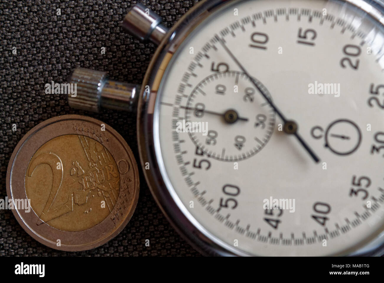 Pièce en euros d'une valeur nominale de deux euro et chronomètre sur toile Denim marron - business background Banque D'Images