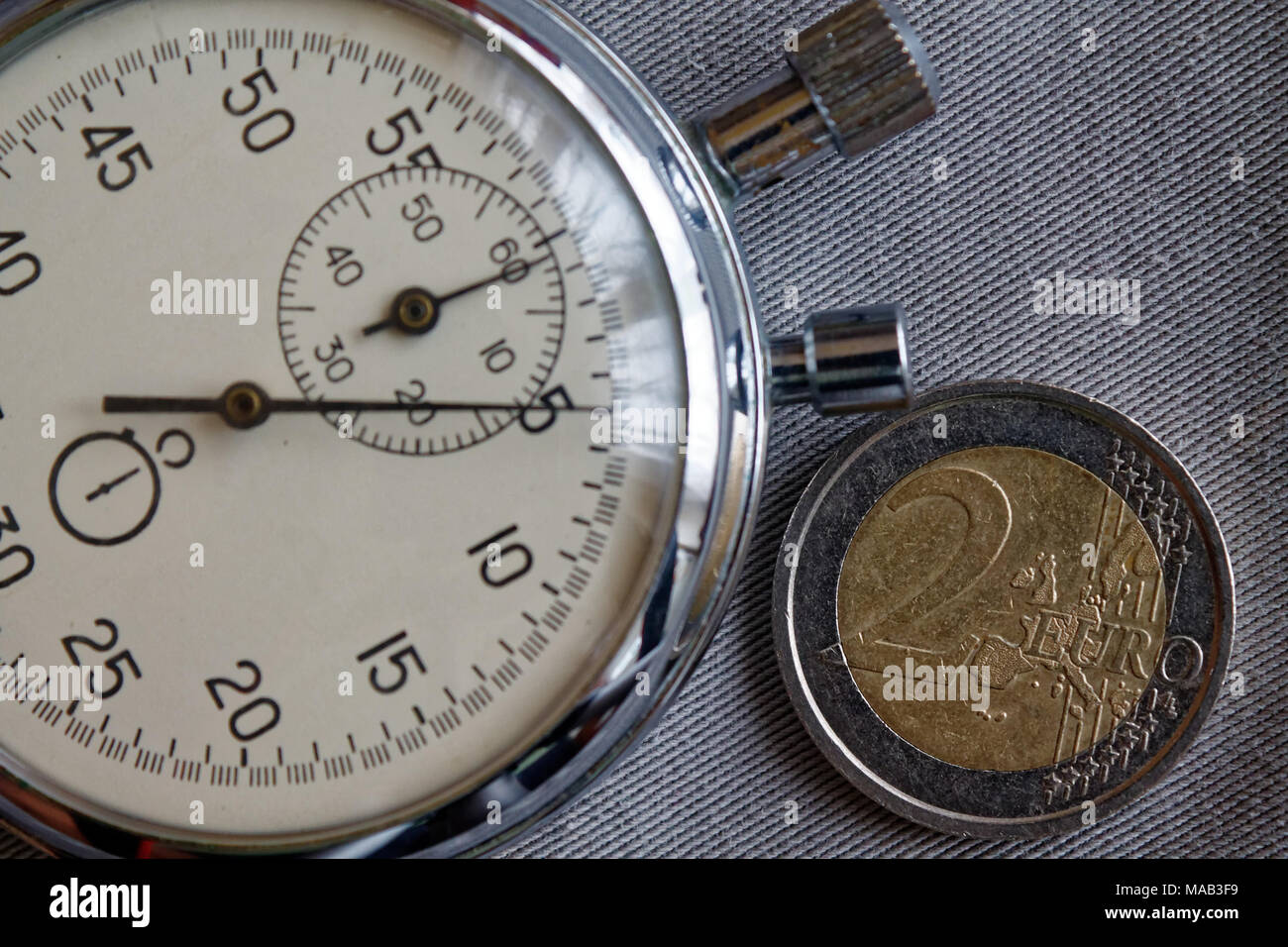 Pièce en euros d'une valeur nominale de deux euro et chronomètre sur toile Denim gris - business background Banque D'Images