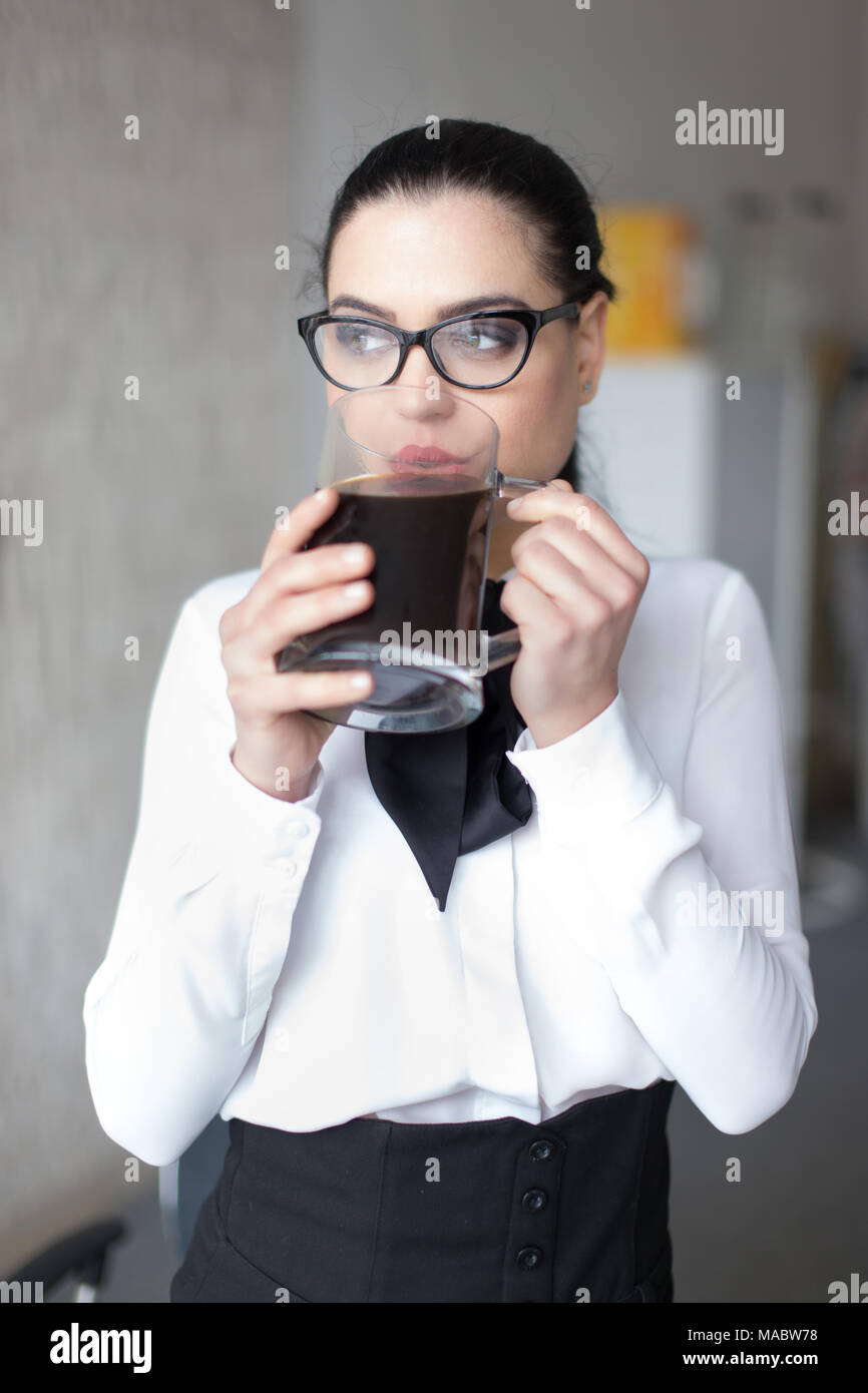 Jeune femme intelligente dans les lunettes grand potable tasse de café, à l'écart Banque D'Images
