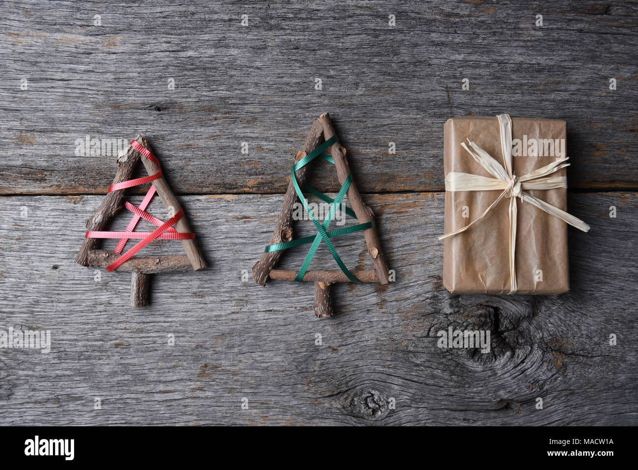 Deux arbres de Noël des rameaux et une plaine enveloppé dans du papier présent sur une table en bois rustique. Banque D'Images