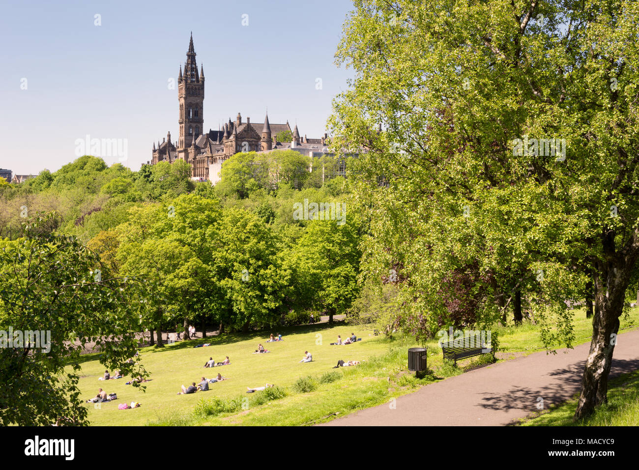 Les jeunes, les étudiants de l'Université de Glasgow bénéficiant d'une chaude journée ensoleillée sur les pelouses du parc de Kelvingrove, l'université dans l'arrière-plan Banque D'Images