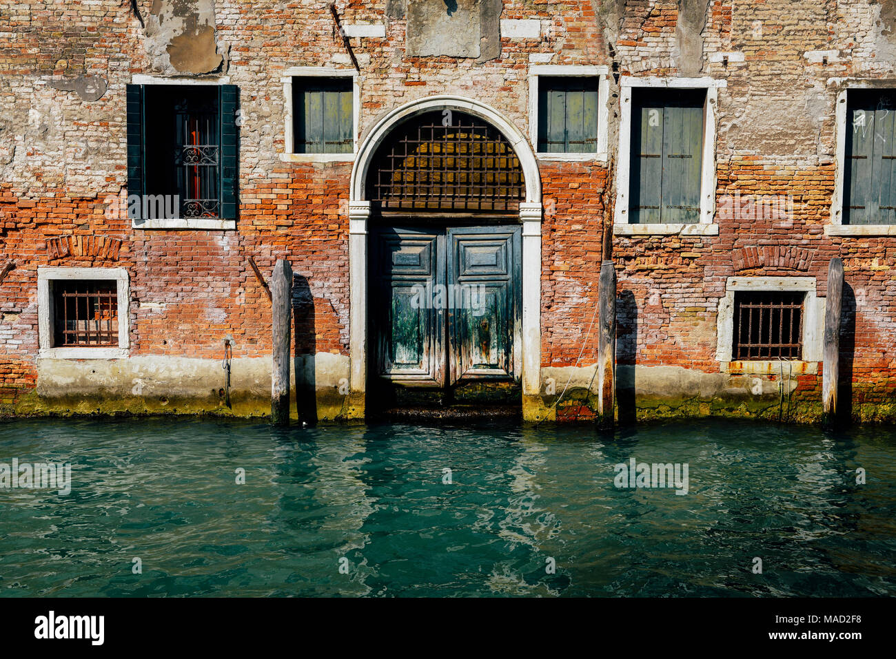 Façade de maison en briques anciennes moussus partiellement avec du vintage porte à petit canal à Venise, Italie. Banque D'Images