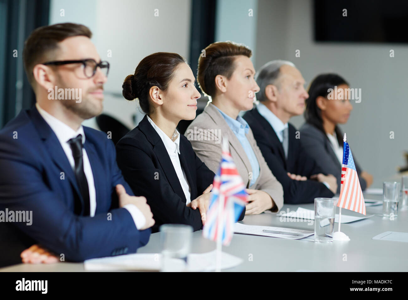 Groupe de représentants internationaux en soirée à écouter attentivement rapport de l'un des orateurs au sommet politique Banque D'Images