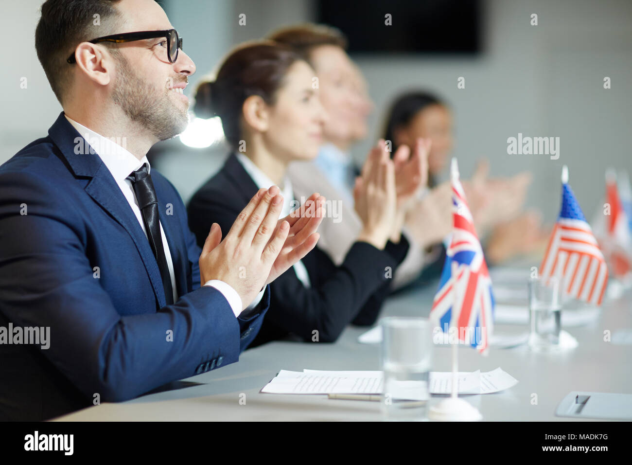 Jeune délégué et ses collègues clapping hands à l'orateur à la conférence politique ou sommet Banque D'Images