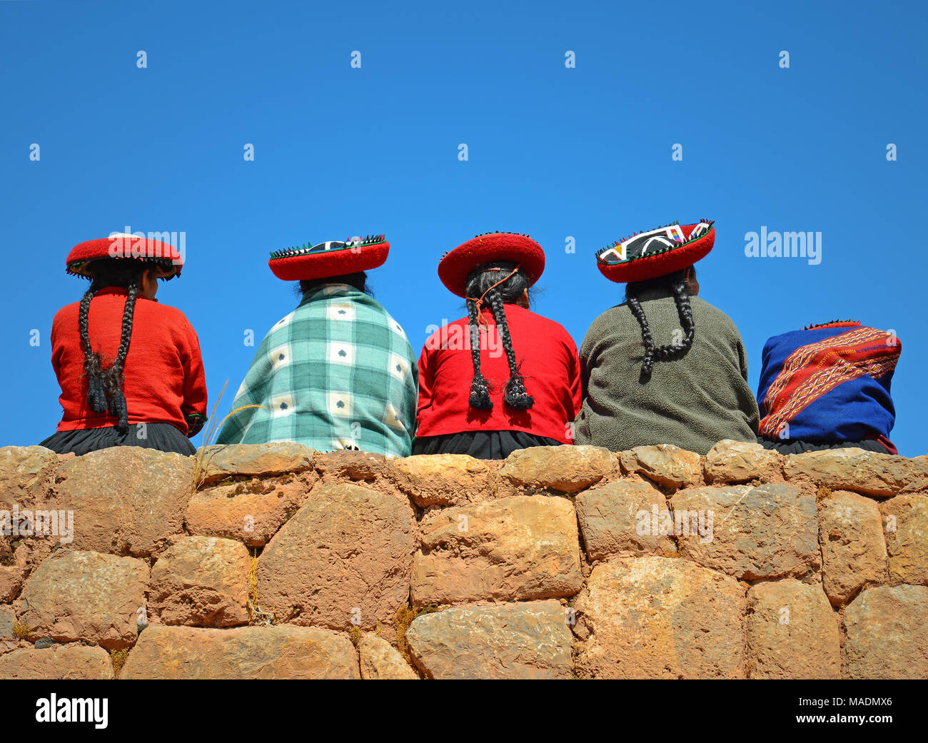 Un groupe de femmes autochtones Quechua assis sur un ancien mur Inca dans le site archéologique de Chicheros près de la ville de Cuzco, Pérou, Amérique du Sud. Banque D'Images