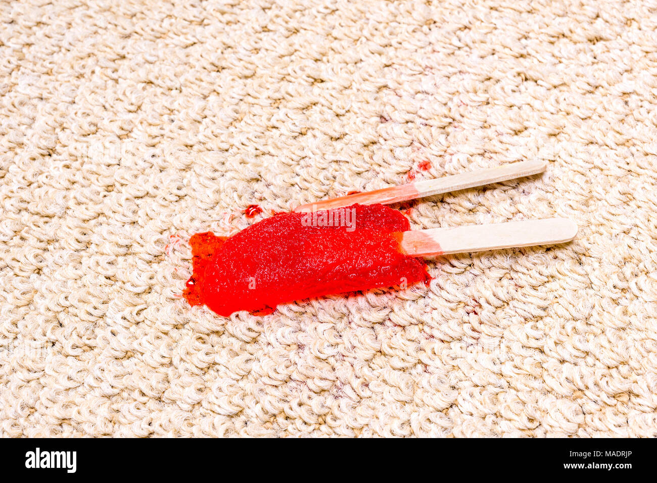 Un laps de temps d'un popsicle de fusion sur tapis blanc montre l'icy traiter se fondent dans un jus collant et absorber droite dans le tapis. Banque D'Images