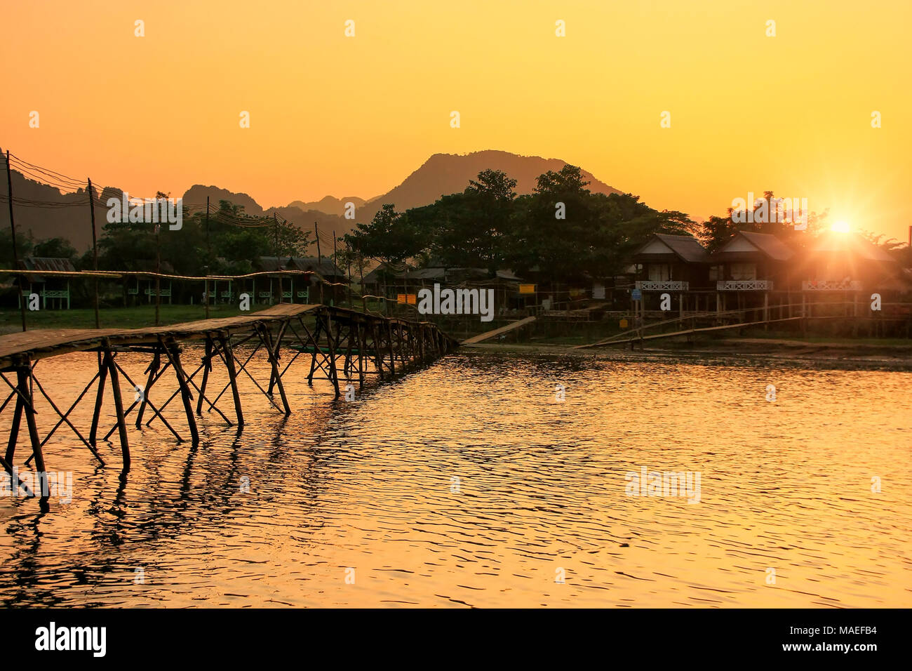 La rivière Nam Song avec pont en bois au coucher du soleil à Vang Vieng, Laos. Vang Vieng est une destination populaire pour le tourisme d'aventure dans un paysage karstique calcaire Banque D'Images