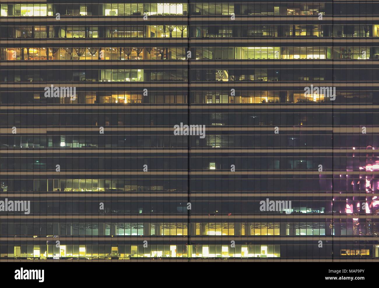 Office building Vue de côté. Les personnes qui travaillent pendant la nuit en façade mur en verre moderne tour moderne. Banque D'Images