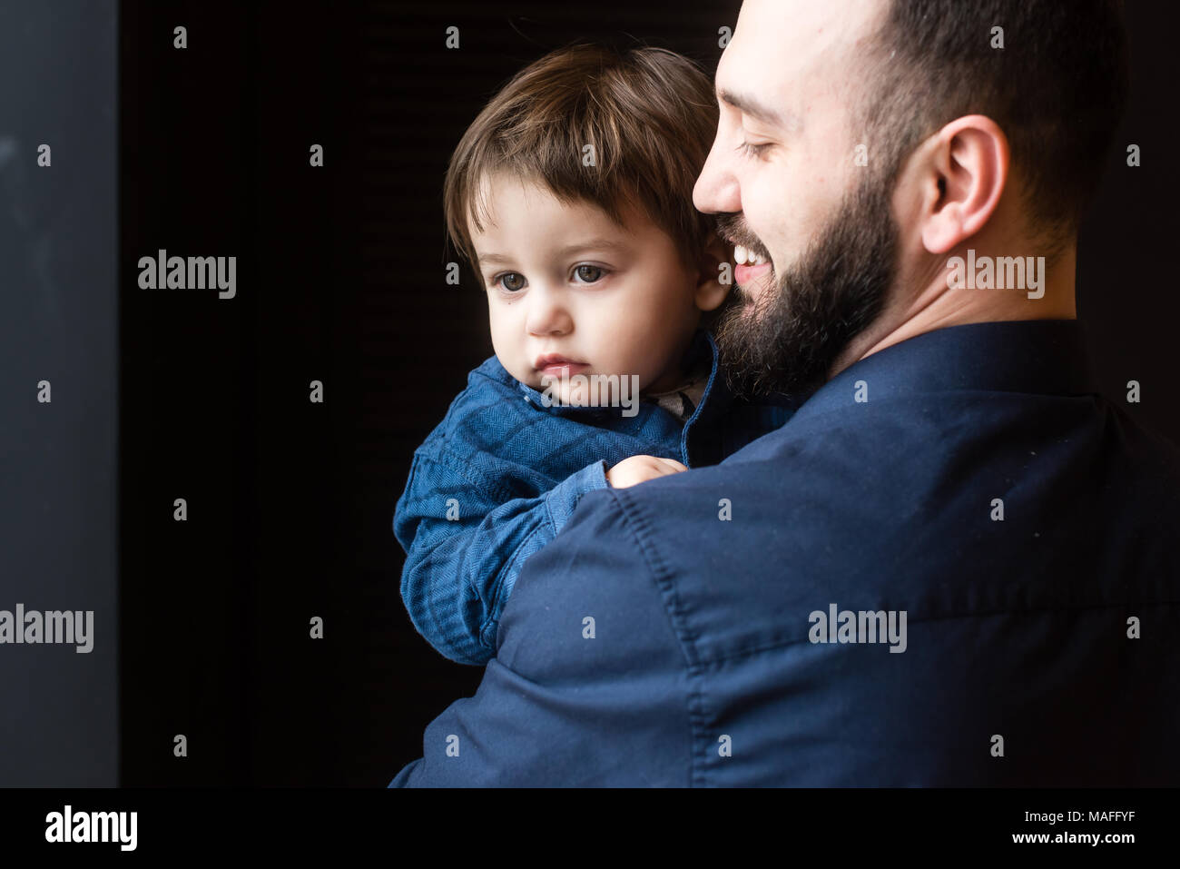 Pere Et Fils Dans La Region De Calins A Fond Noir Petit Garcon Dans Les Bras Du Pere Papa Sourit A Son Petit Enfant Photo Stock Alamy