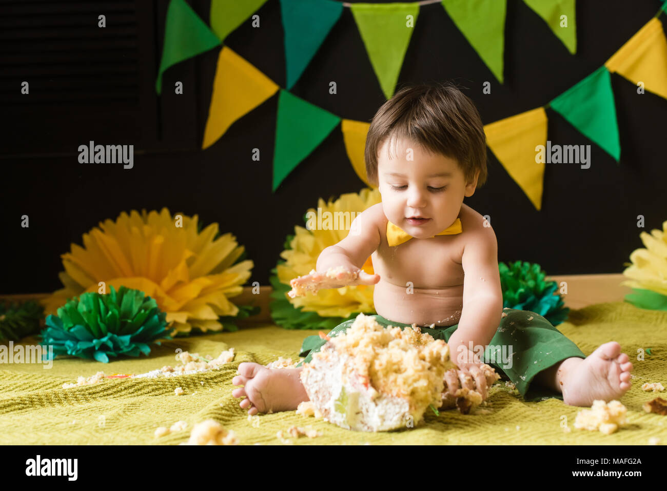 Bébé avec bow détruire gâteau sucré en jaune et vert décoration. Smash gâteau Banque D'Images