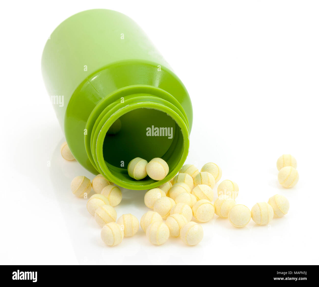 Les comprimés de probiotiques ronde jaune déversant du vert bouteille de médicament contre l'arrière-plan blanc. Banque D'Images