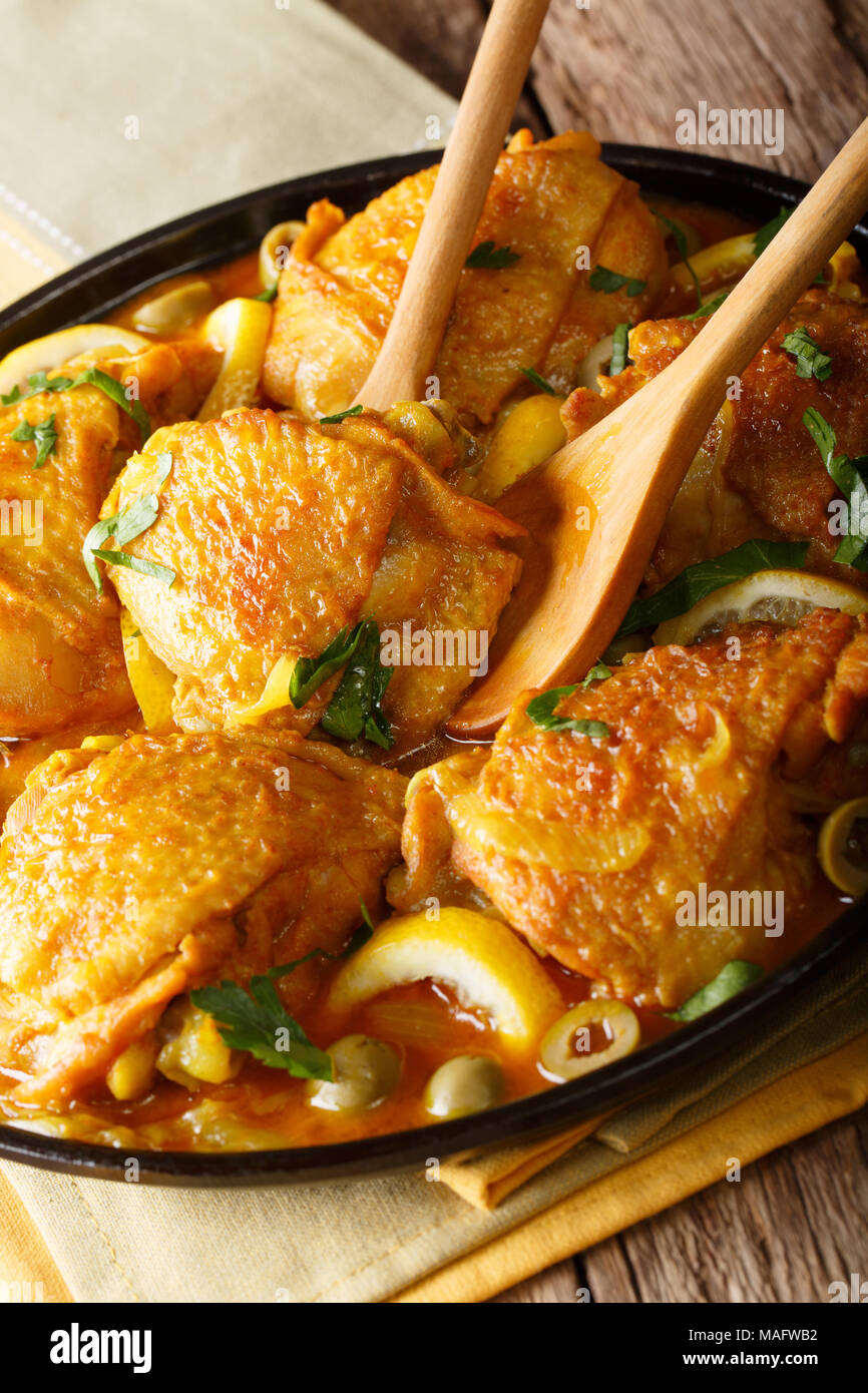 Tajine de poulet aux citrons salé, les oignons et les olives vertes close-up sur la table verticale. Banque D'Images