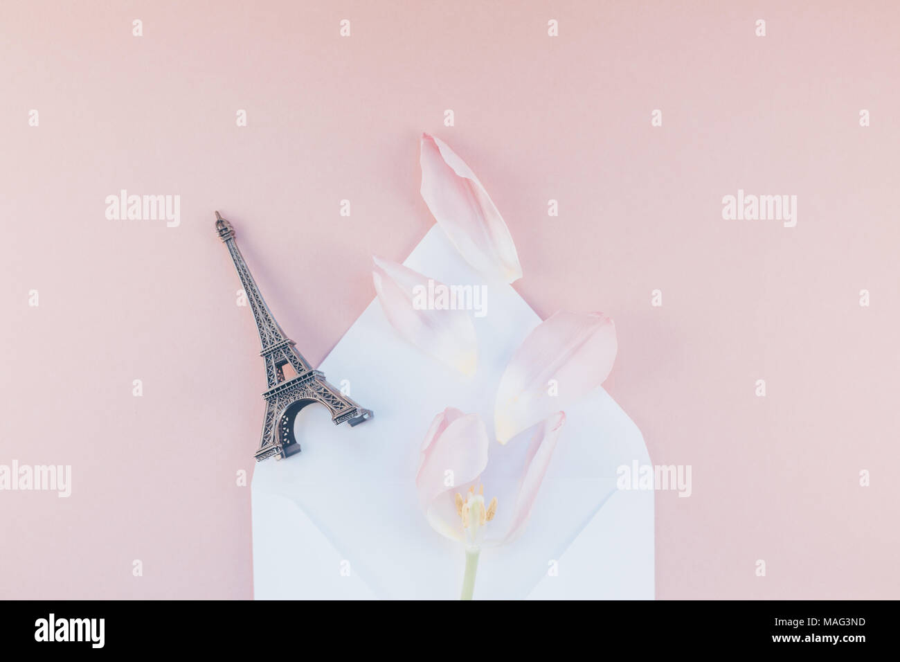 Tulipe rose avec pétales de papier enveloppe lettre ouverte avec tour Eiffel miniature sur un fond rose. Télévision jeter dessus. Souvenirs d'amour romantique con Banque D'Images