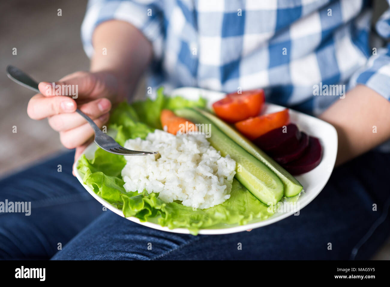 Fille avec une assiette de légumes en mains Banque D'Images