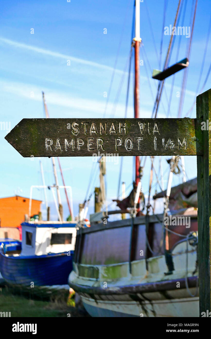 Ancienne en bois panneau indiquant la direction de Stanah via Ramper Pot avec mâts de bateau en arrière-plan, Thornton, Lancashire, Royaume-Uni Banque D'Images