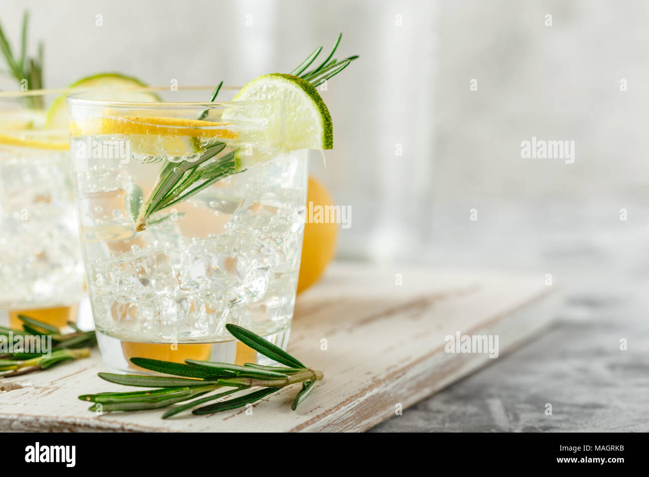 Boisson alcoolisée avec citron et rosemain, dans les verres sur une table lumineuse Banque D'Images