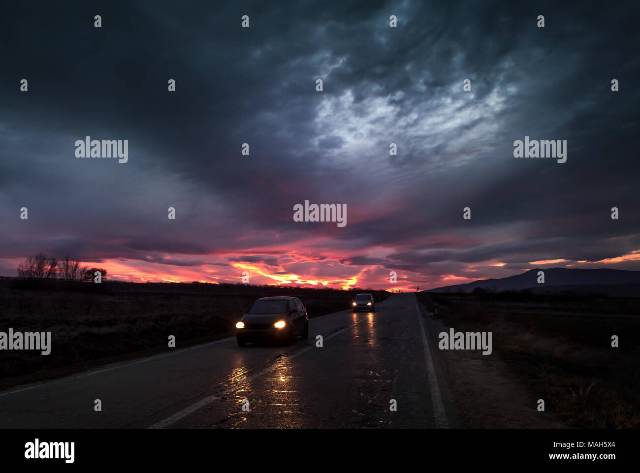 Tout droit à une autoroute près de sunset fiery dramatique crépuscule avec voitures qui passent Banque D'Images